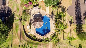An aerial view of a property with a swimming pool, lounge chairs, and palm trees. - Turtle Bay Renovated Luxury Condo • Walk to Beach • King Bed • AC •  (Kahuku)