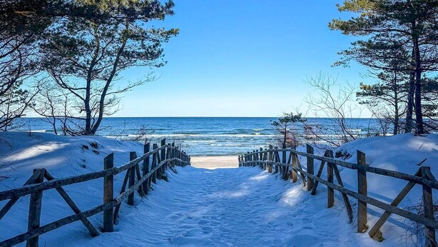 A snow-covered pathway leading to a beach with a wooden fence on either side. - Stunning home in Dmuchowo with WiFi (Dmuchowo)