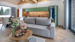 A modern living room with a sofa, a coffee table, and a dining area with chairs. - Stunning home in Dmuchowo with WiFi (Dmuchowo)