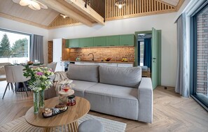 A modern living room with a sofa, a coffee table, and a dining area with chairs. - Stunning home in Dmuchowo with WiFi (Dmuchowo)