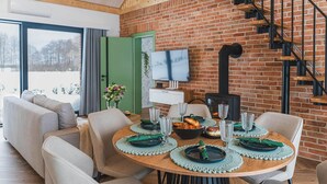 A dining area with a brick wall, a fireplace, a TV, and a staircase. - Stunning home in Dmuchowo with WiFi (Dmuchowo)