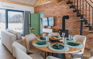 A dining area with a brick wall, a fireplace, a TV, and a staircase. - Stunning home in Dmuchowo with WiFi (Dmuchowo)