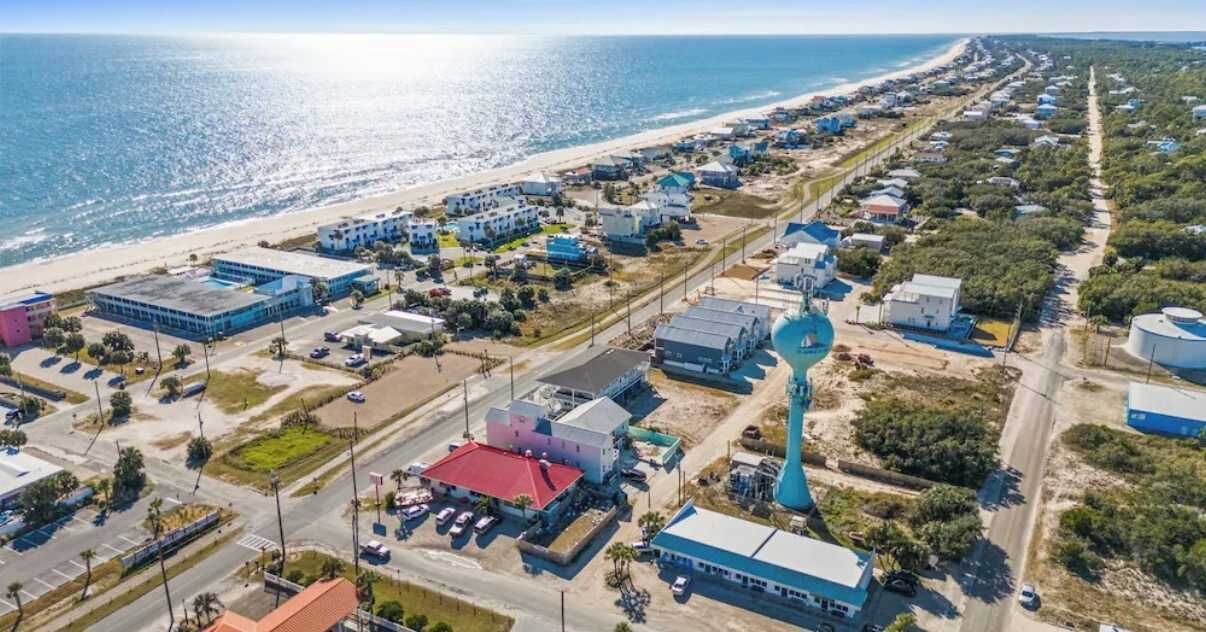 Vista aérea de una zona costera con edificios, una playa y una carretera.
