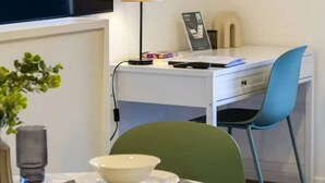 Una camera moderna con TV a schermo piatto, una scrivania con sedia, un tavolo con ciotole, una lampada e un orologio a parete.