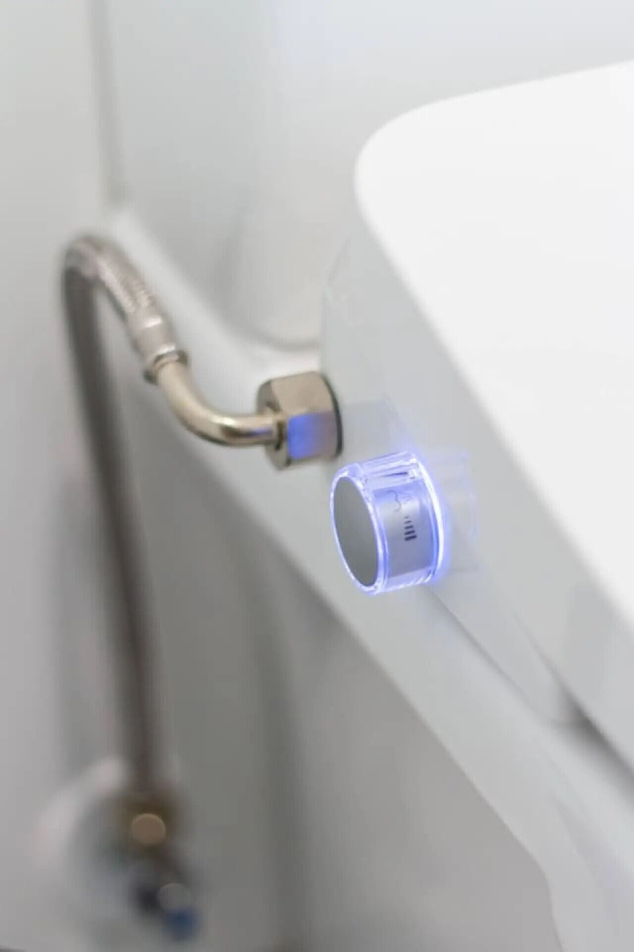 A bathroom with a white sink, a faucet, and a blue-lit water valve.