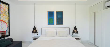 A modern bedroom with a large bed, two wall art pieces, a ceiling fan, and a black pendant light.