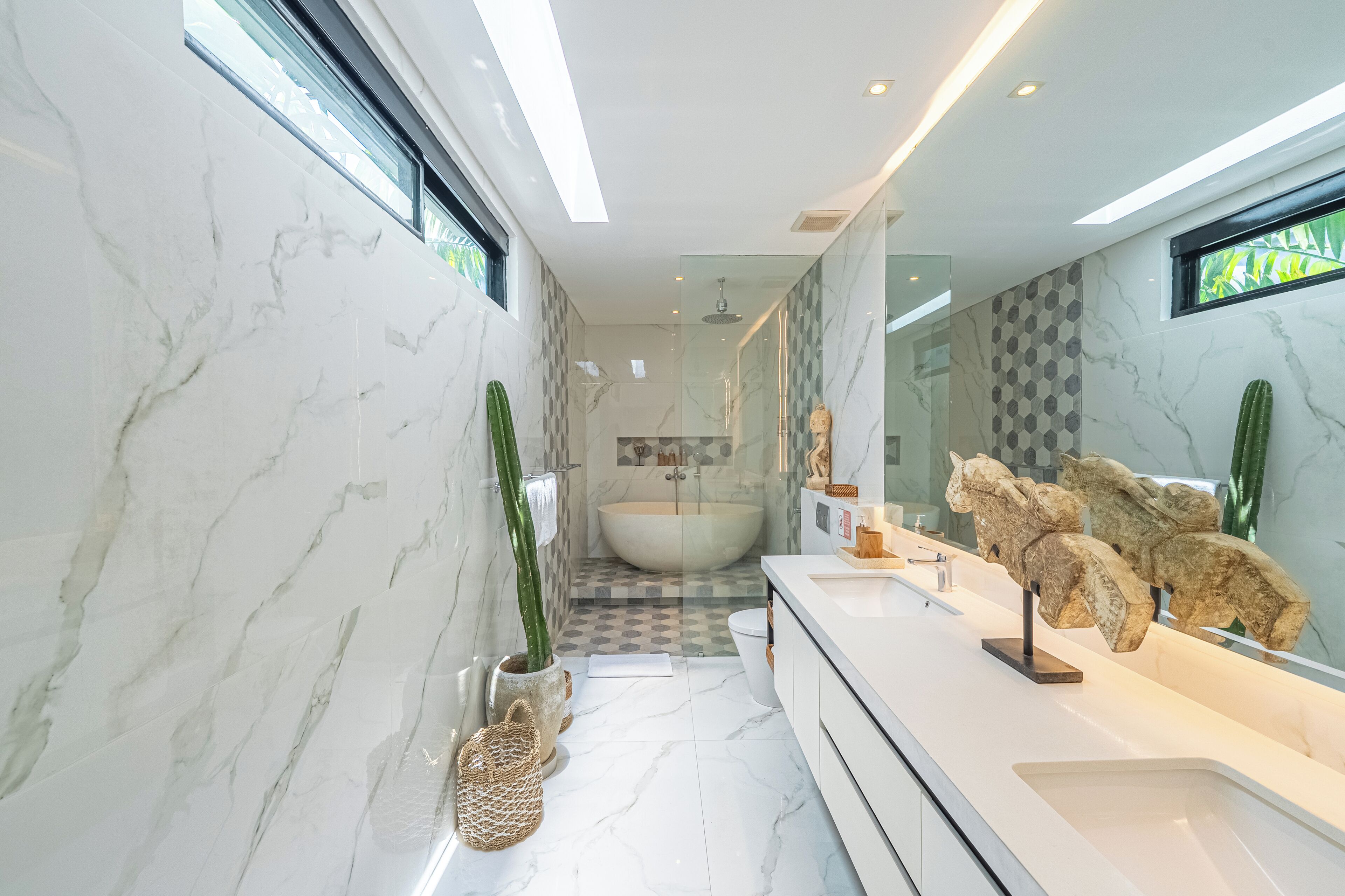 Un baño moderno con una bañera grande, un tocador con espejo y adornos decorativos.