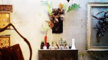 A room with a chandelier, a cabinet with glassware, and a plant on the wall.