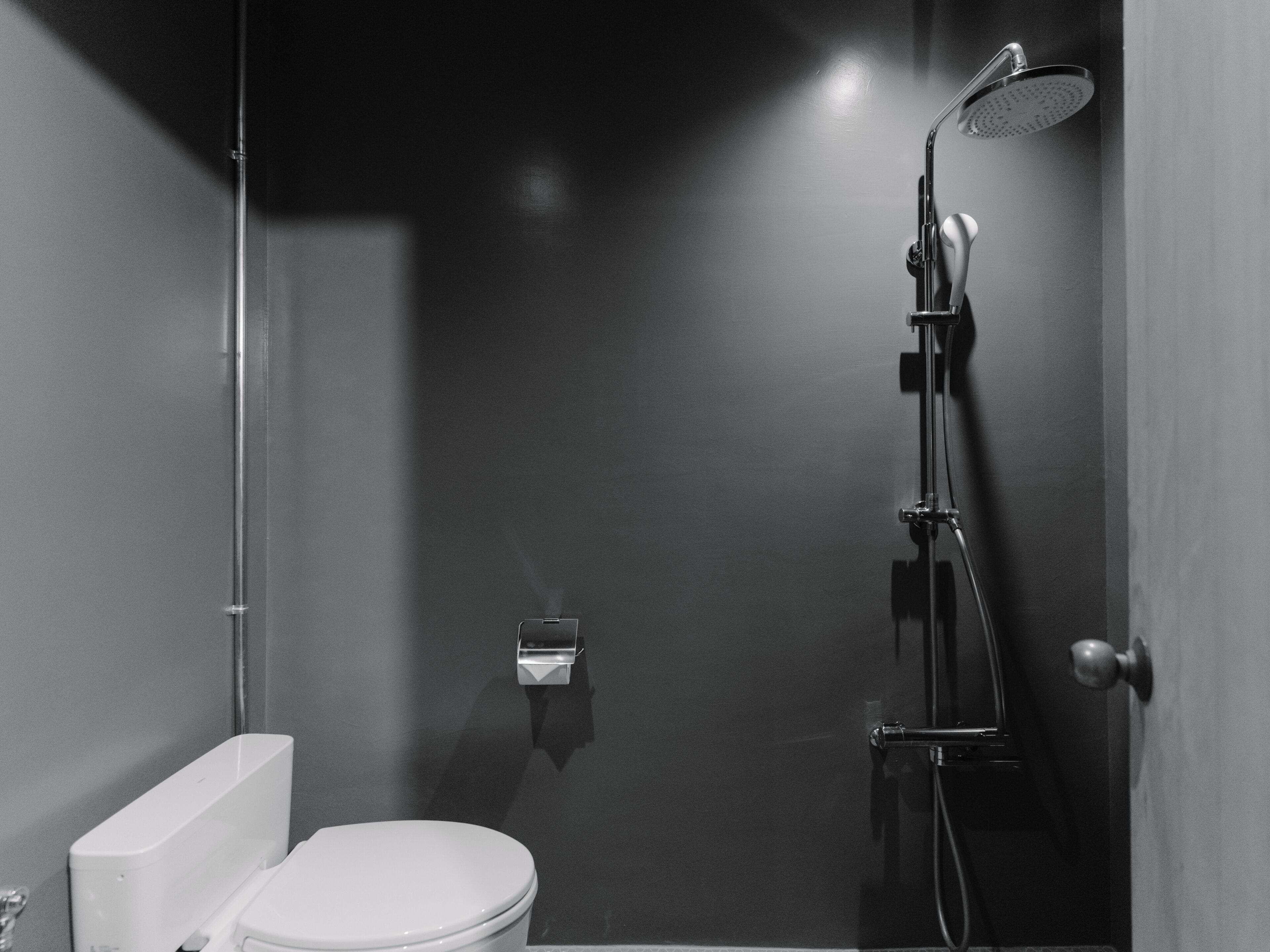 A modern bathroom with a toilet, a shower, and a towel dispenser.