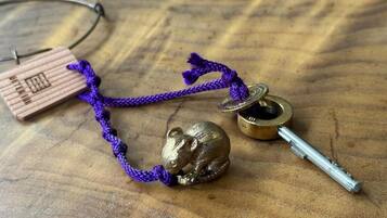 A wooden keychain with a mouse figurine, a small metal container, and a purple cord.