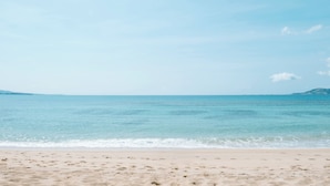Uma praia com céu claro e mar calmo.