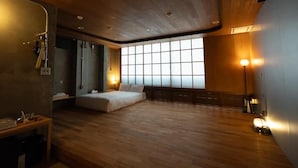 Quarto com teto de madeira, janela ampla, cama e escrivaninha.