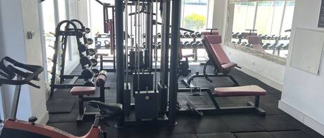 A gym with exercise equipment, benches, and a weight rack.