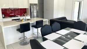 Une cuisine moderne avec des meubles blancs, un réfrigérateur en acier inoxydable et un pare-feu rouge.