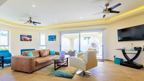 A spacious living room with a sofa, armchair, coffee table, and ceiling fan. - Casa Elegante Luxury Villa (Isla Mujeres)