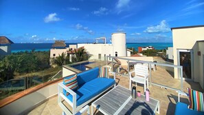 Une terrasse sur le toit avec une piscine, un espace salon et une vue sur l’océan.