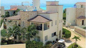 A multi-story building with a stone facade, balconies, and a view of the sea. - Casa Elegante Luxury Villa (Isla Mujeres)