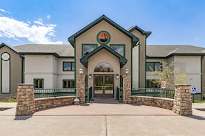 A building with a prominent entrance, stone pillars, and a wheelchair-accessible sign.