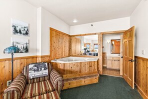 Una habitación con una bañera de madera, un sofá a rayas y un espejo que refleja la zona de la cocina.
