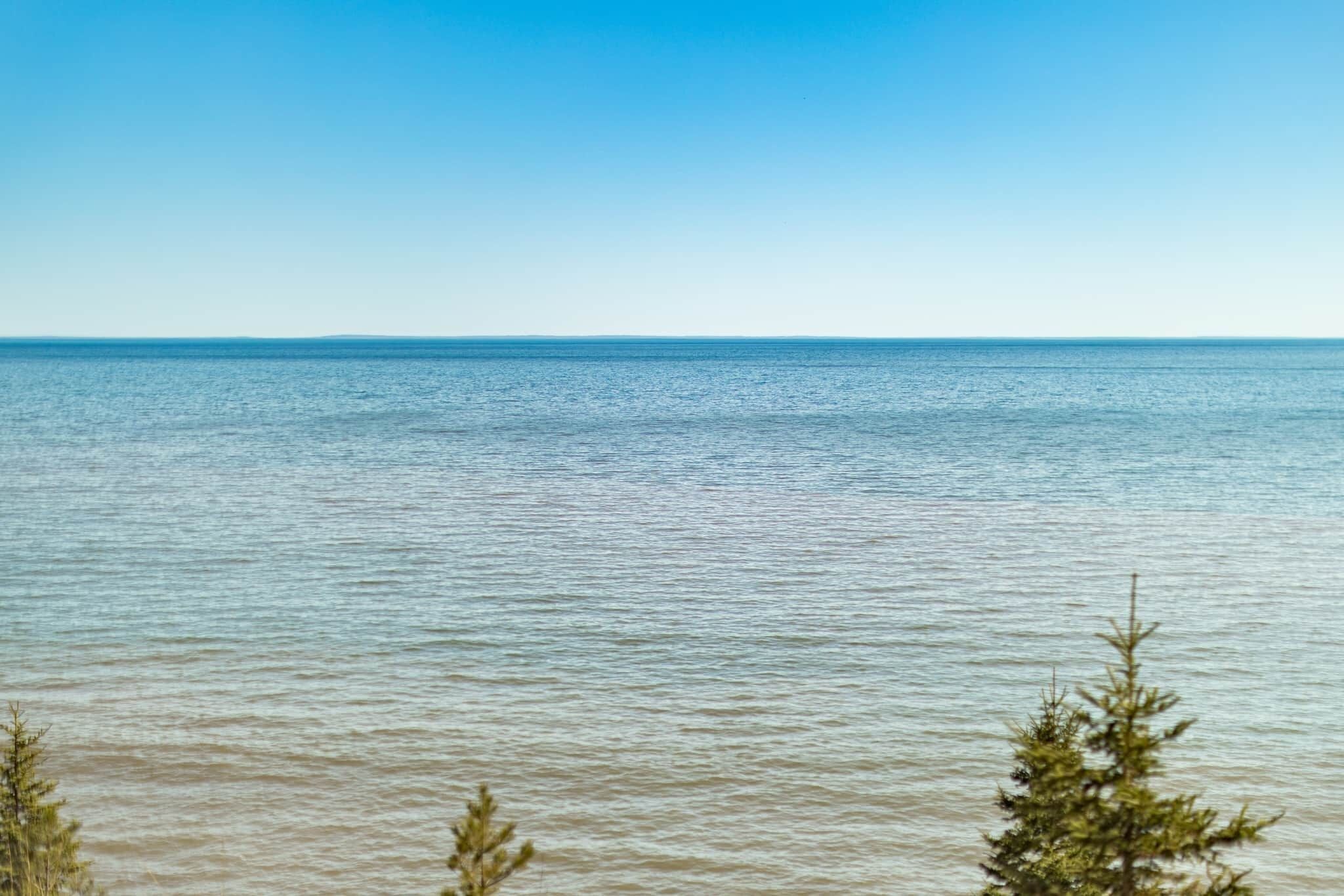 Ruhige Wasserfläche mit blauem Himmel und einer fernen Küste.