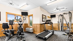 Une salle de sport équipée de tapis de course, de vélos elliptiques et de matériel de musculation.