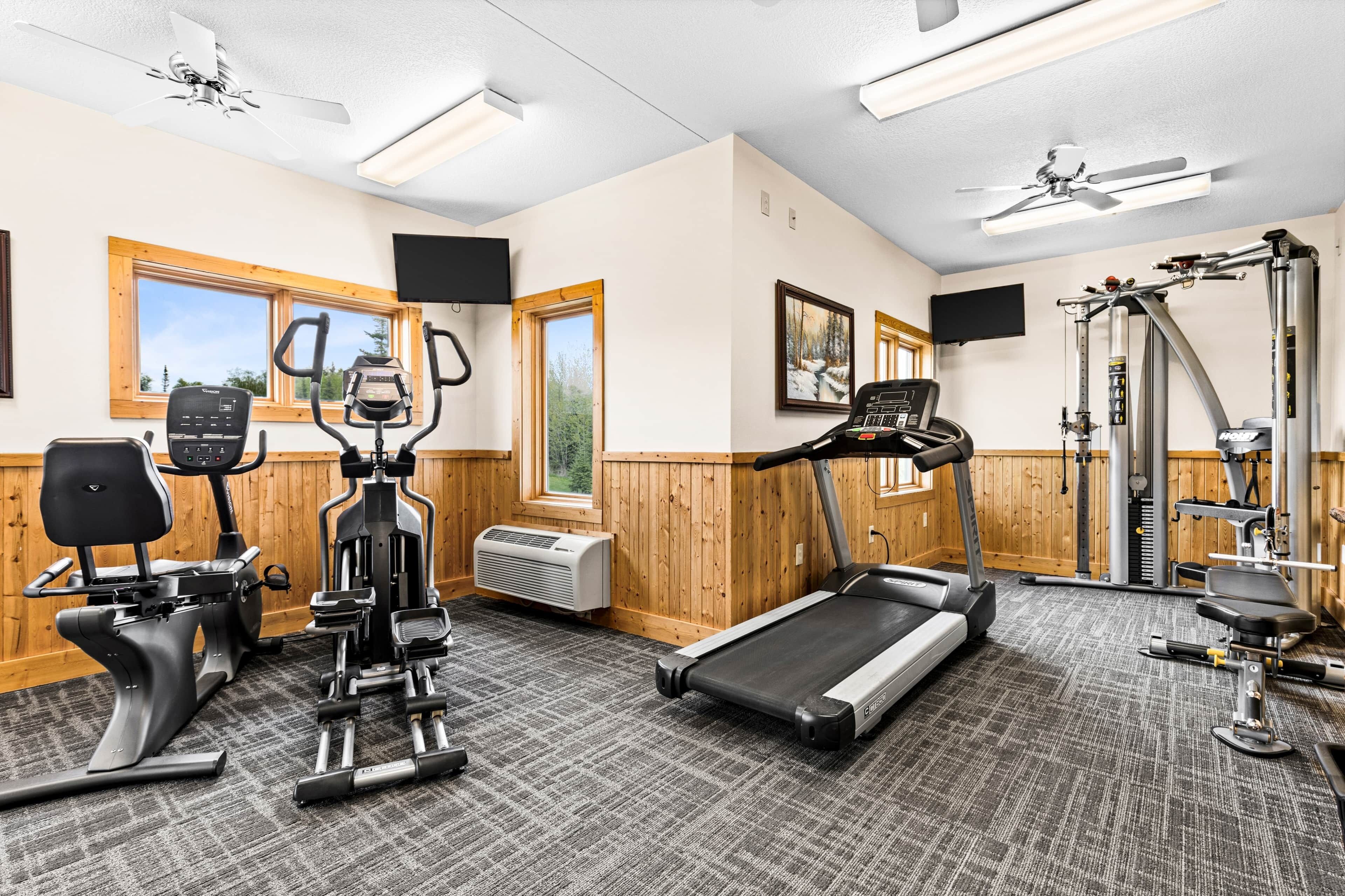 A gym with exercise equipment, a treadmill, and a wall-mounted TV.
