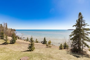 Une vue sur le lac, avec des arbres, un ciel dégagé et une rive lointaine.