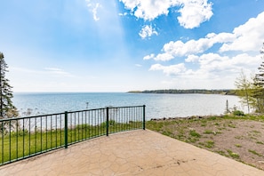 Une zone d’observation aménagée avec une surface pavée et une rambarde métallique, d’où l’on peut admirer un plan d’eau et le paysage lointain.