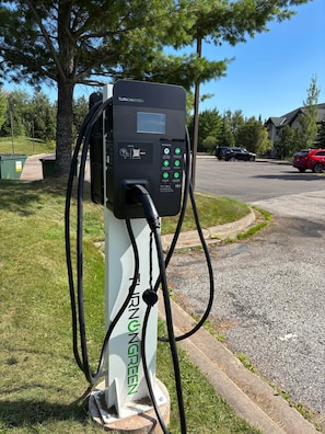 Una estación de carga pública para vehículos eléctricos, con una interfaz clara y un cable conectado a un automóvil.
