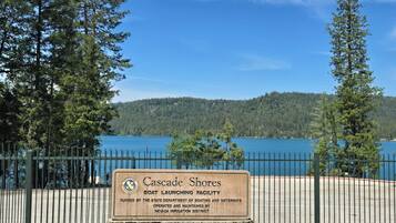 Un panneau indiquant l’emplacement de la zone d’accès à l’eau pour les bateaux de Cascade Shores, avec une vue sur un lac et des collines boisées.