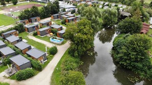 Un quartier résidentiel composé de maisons modernes disposées autour d’un plan d’eau central, le tout entouré d’une végétation luxuriante.
