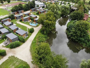 Een woonwijk met moderne huizen rond een centraal waterpartij, omgeven door weelderige begroeiing.