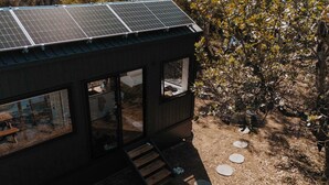 Una casa moderna con pannelli solari, ampie finestre e un terrazzo in legno.