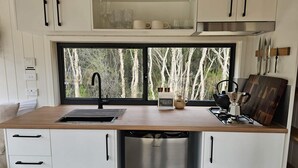 Eine moderne Küche mit einem Edelstahl-Geschirrspüler, einem Einbauofen und einem Fenster mit Blick auf Bäume.