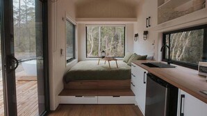 Ein kleines Schlafzimmer mit integriertem Bett, einem kleinen Tisch und Blick ins Freie.