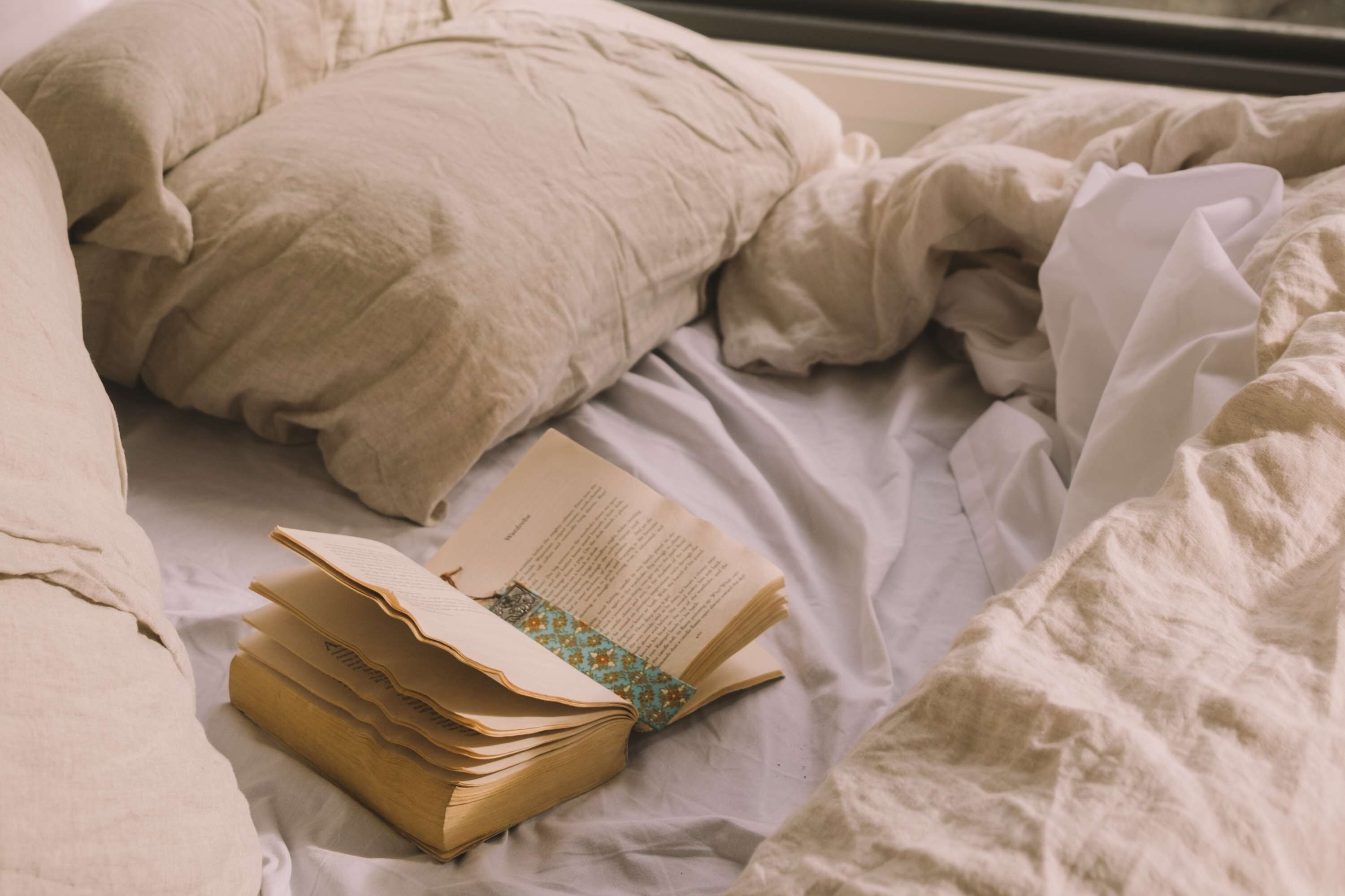 A bed with a book and pillows.
