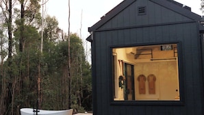 Eine kleine, dunkle Holzhütte mit einem großen Fenster, das einen Innenraum mit einer Tür und zwei Holzpaneelen zeigt.