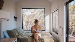 Quarto com cama, janela e vista para árvores.