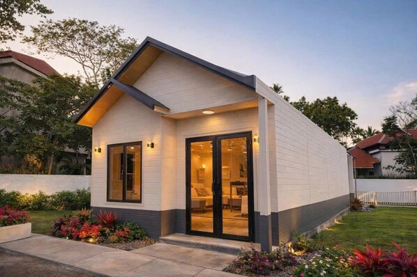 A modern house with a sloped roof, large glass doors, and a well-maintained garden.