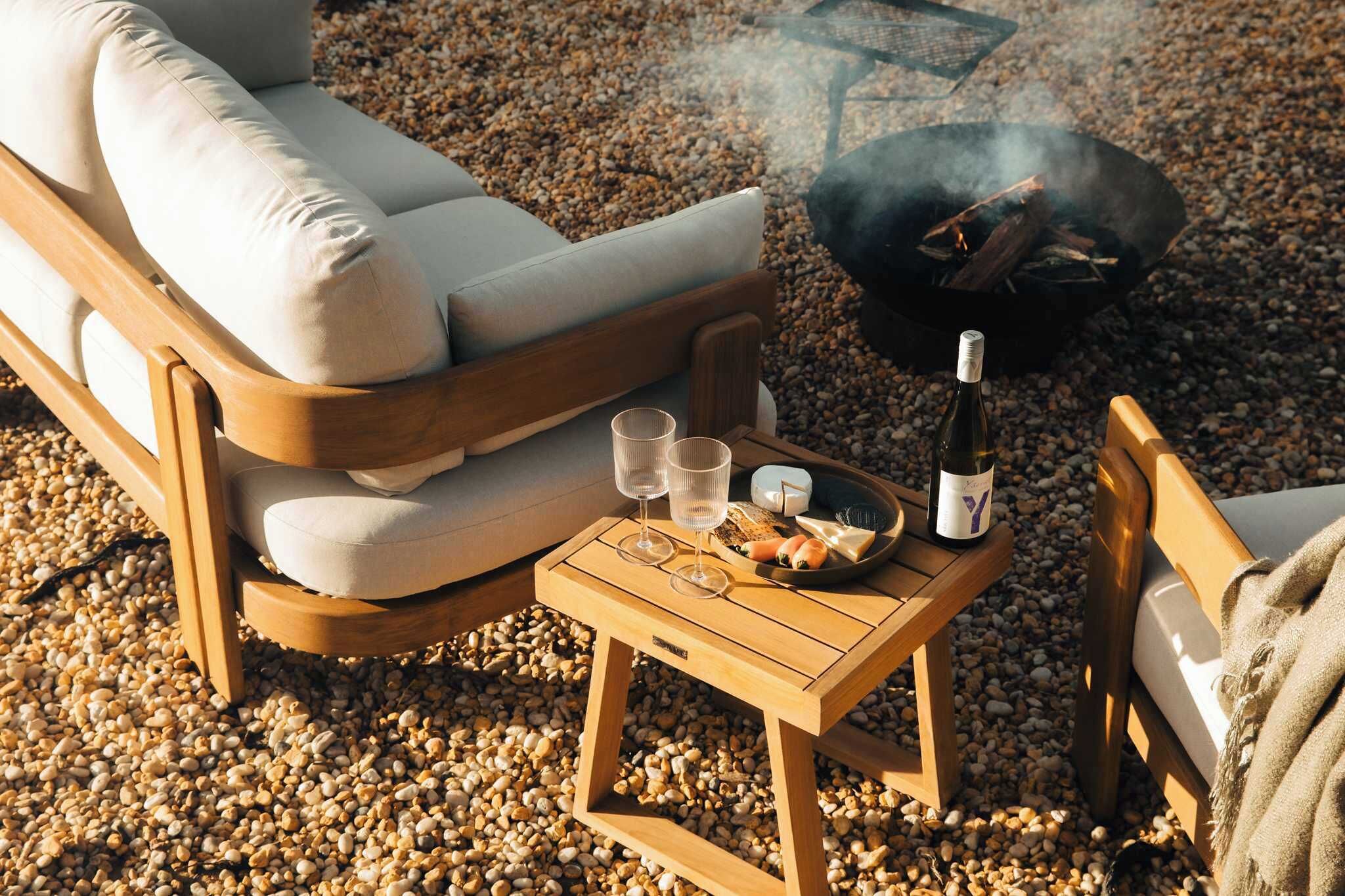 Een houten terras met een barbecue, twee glazen, een fles en een bord met eten.