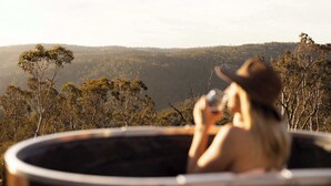 Une personne dans un bain à remous, avec vue sur un paysage boisé.