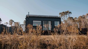 Un bâtiment moderne doté de grandes fenêtres, entouré d’une végétation aride.