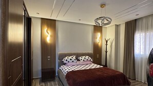 Un dormitorio moderno con cama, suelo de madera y un diseño de techo singular.