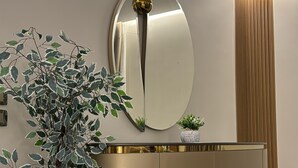 Un interior moderno con un mueble dorado, un espejo grande y una planta en maceta.