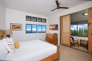 Une chambre à coucher avec un lit, une commode, un téléviseur et une fenêtre donnant sur un beau paysage.