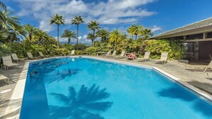Ein Schwimmbad mit Liegestühlen und Palmen.