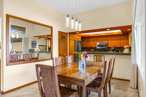 Un comedor con mesa y sillas de madera, un espejo grande y una cocina con armarios y electrodomésticos de madera.