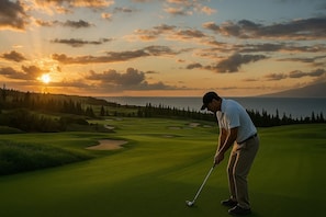 Een golfbaan met uitzicht op een zonsondergang, een waterpartij en een bebost gebied.