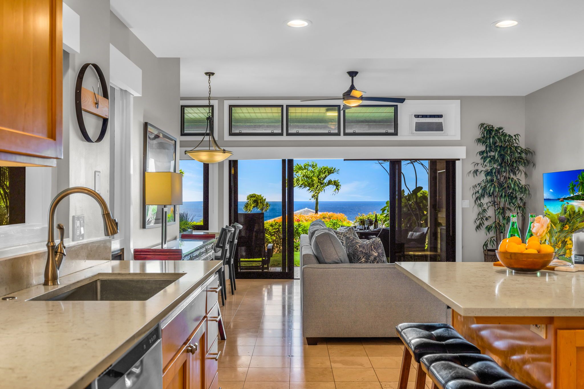 Una cocina moderna con una isla grande, un comedor con vistas y un espacio de sala con un sofá y televisor.