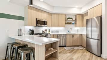 A modern kitchen with a central island, stainless steel appliances, and wooden cabinetry.